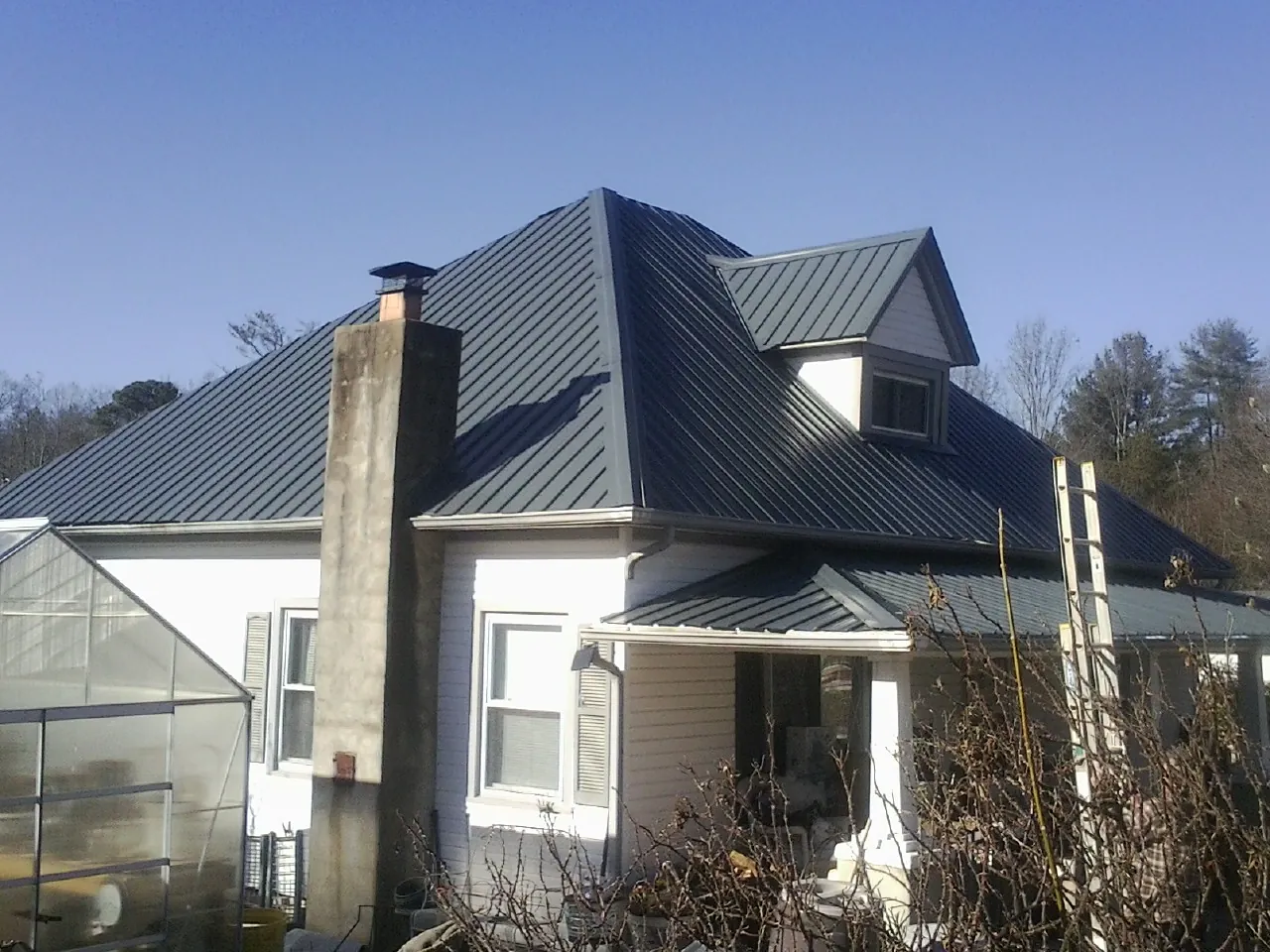 Dark blue standing seam metal roof on a white farmhouse with dormer — Slate & Tile Roof Repair by Roofing Brothers in Templeton