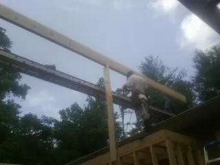 Carpenter setting a ridge beam over a new addition frame — Ice Dam Removal by Roofing Brothers in Templeton